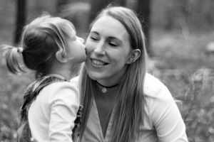 black and white mother daughter portrait with daughter kissing
