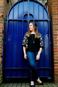 Female full body portrait in front of a bright blue gate