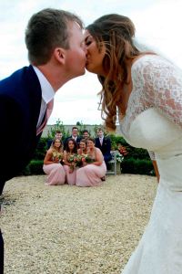 Bride and Groom kissing with group of friends underneath