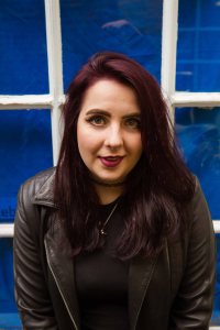 Smiling natural light portrait of model infront of blue window