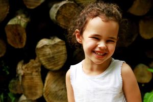Child portrait in front of a stack of logs