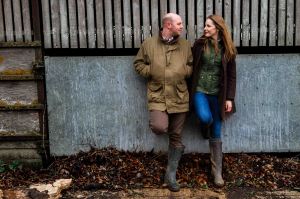 On the farm couple portrait with husband and wife leaning on the barn wall