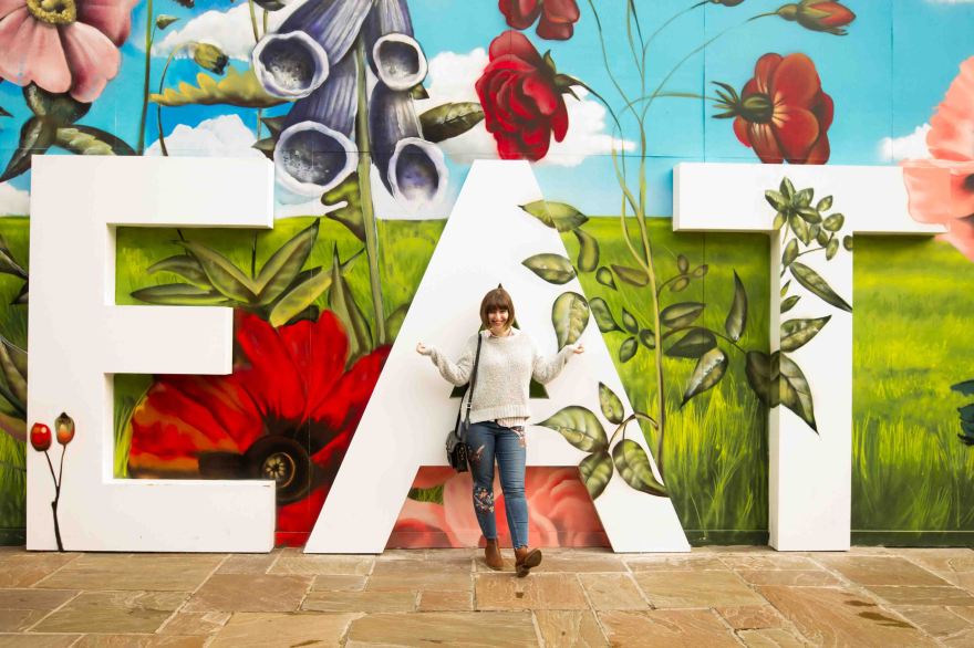 Life of Lilly Blogger standing in front of a sign for Eat