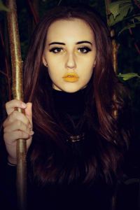 Close up portrait of model with yellow lipstick holding a branch