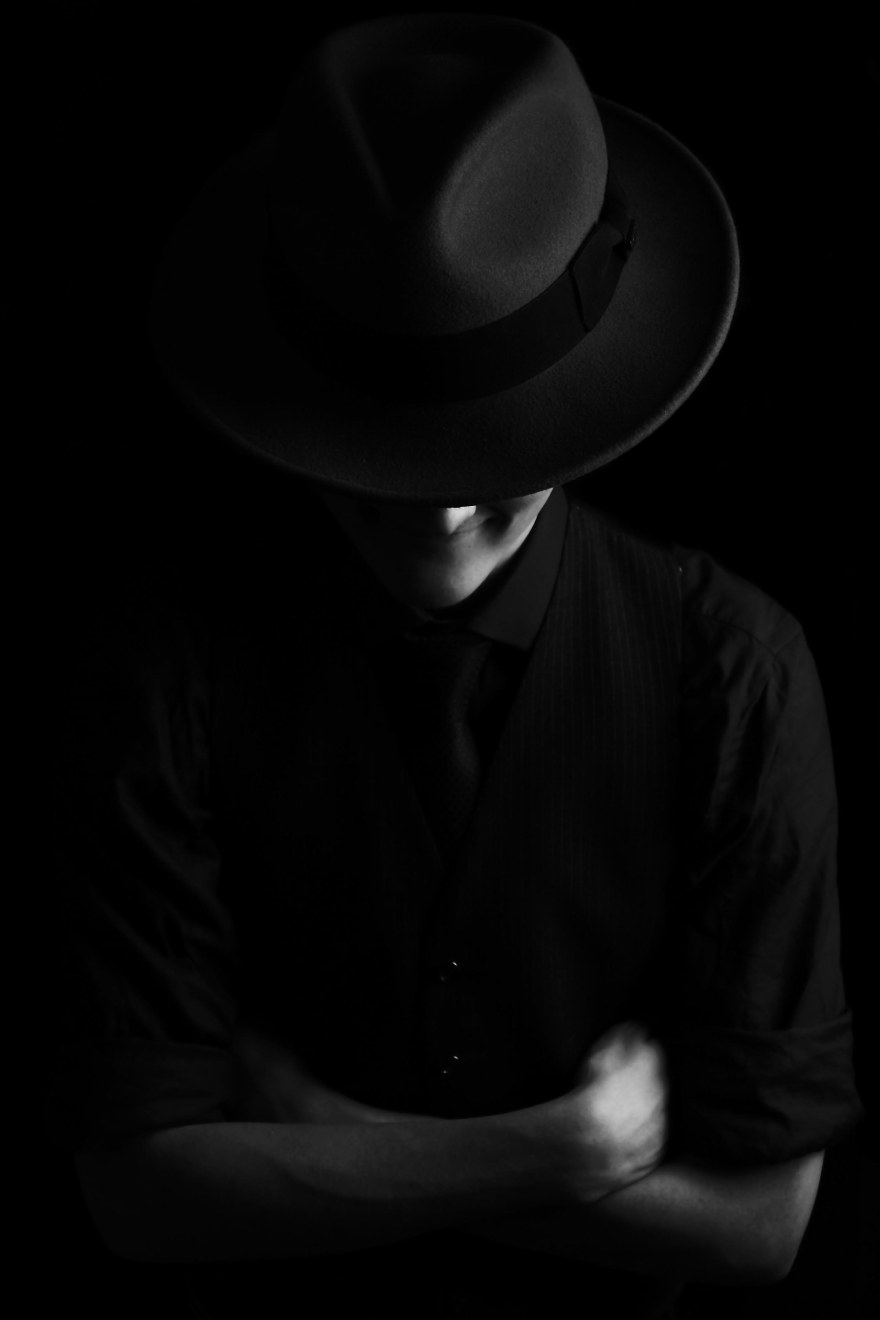 Low key edge lighting black and white portrait of male fedora