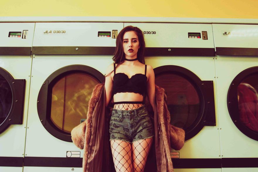 Vintage portrait of model standing in front of the washing machines in a laundrette