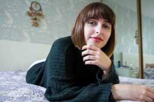 Life of Lilly lying on her bed in her green jumper