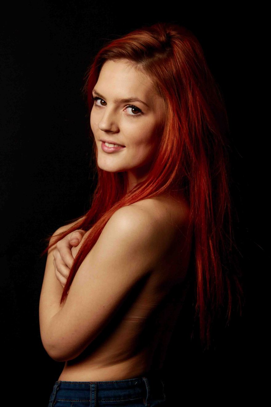 nude portrait of red haired model with low key studio lighting