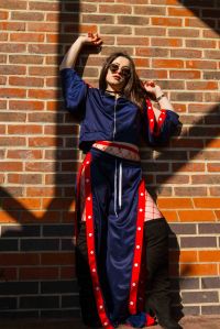 Model lent against a brick wall dressed in blue with natural light framing her