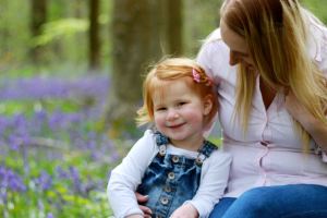 Mother hugging daughter in a field of blue bells