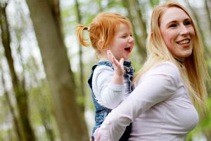Mother giving a daughter a piggy back and the daughter laughing