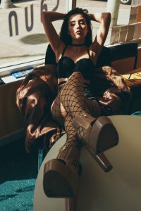 Model posing with her feet on a table in front of a big window