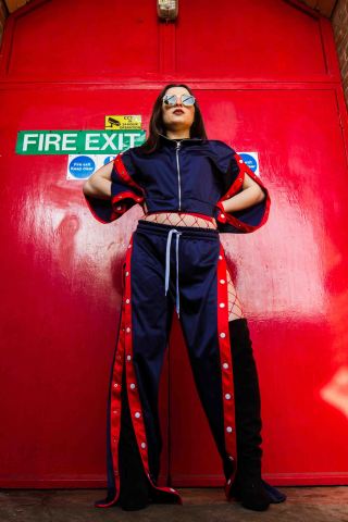 Red and blue fashion editorial portrait with blue tracksuit and red back drop