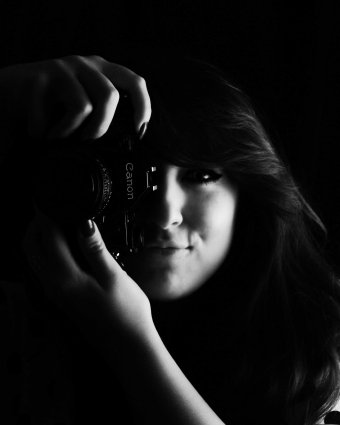 Low key black and white self portrait in studio holding camera