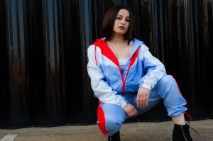 Urban portrait of model knelt in front of black backdrop