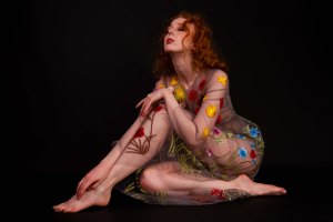 Gemma sat in a studio wearing a floral dress