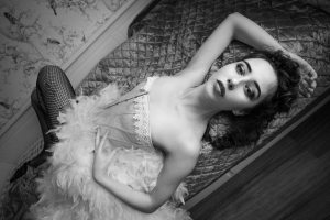 Black and white portrait of model laying across the bed