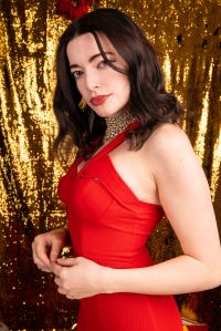 Portrait of model in a red dress side on in front of glitter backdrop