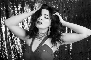 Portrait of model shaking her hair in front of glitter backdrop